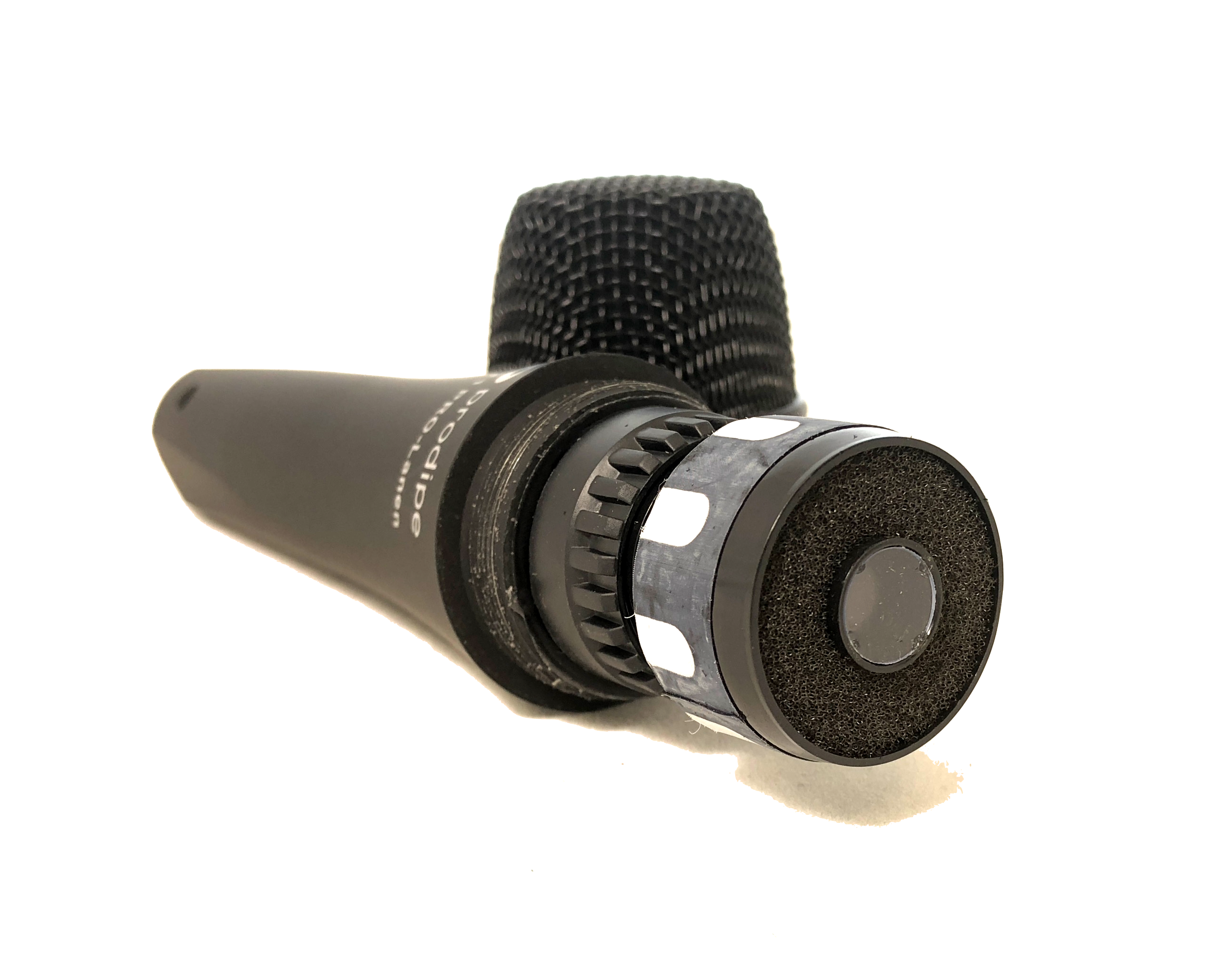Black handheld recording microphone lying on its side, showing the mesh head and round battery compartment at the bottom.