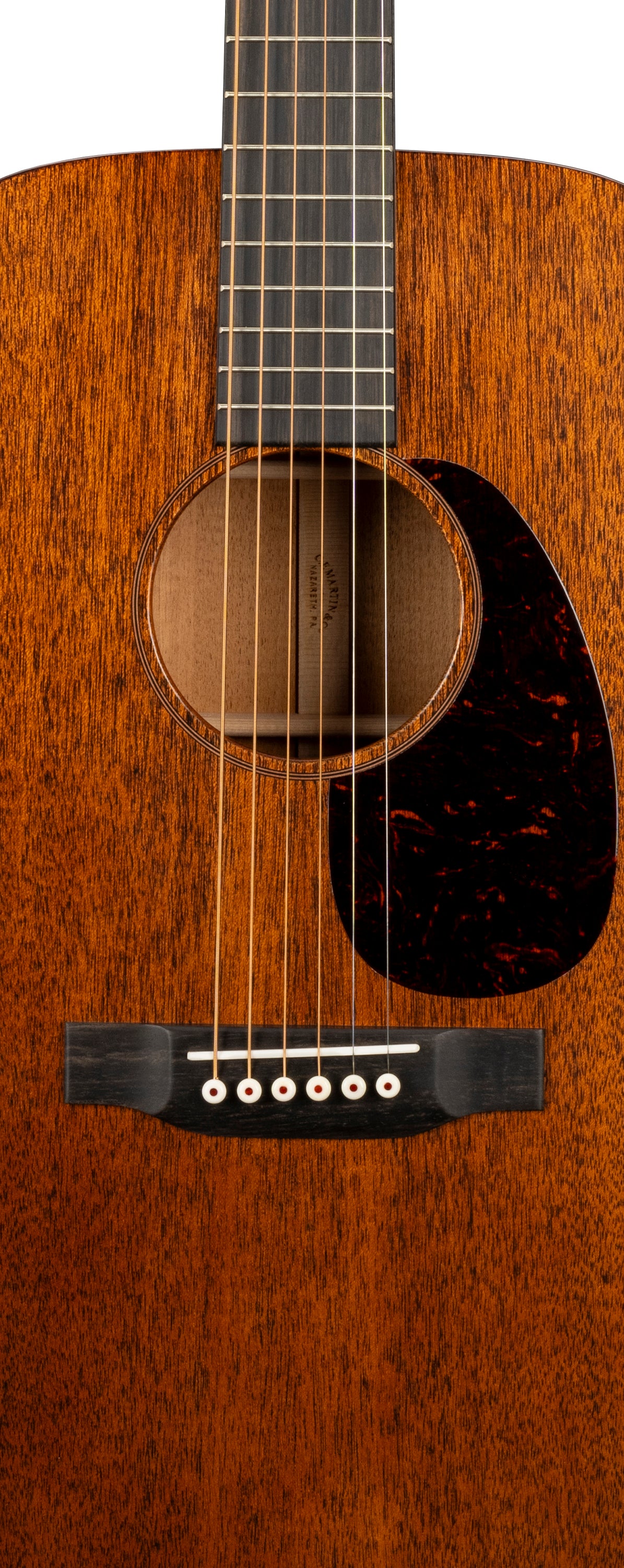 Close-up of an acoustic guitar body showing six strings, a dark brown pickguard, and a wood grain finish with a circular sound hole.
