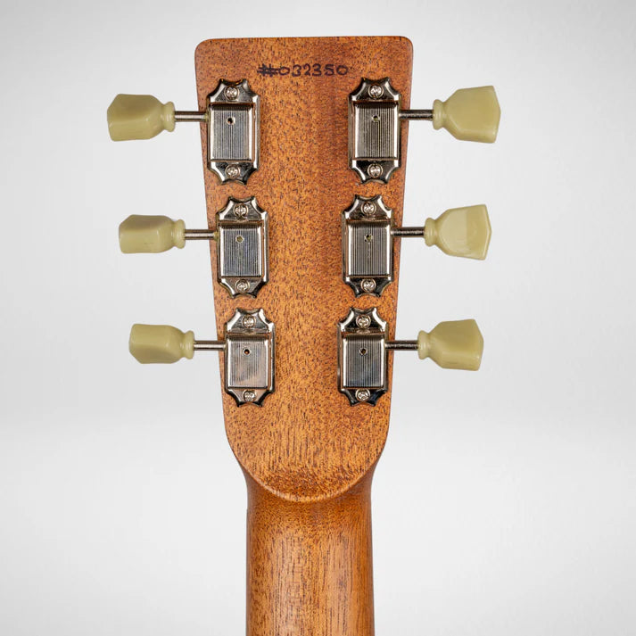 Back of an electric guitar headstock showing six vintage-style tuning pegs with cream knobs and a serial number printed at the top.