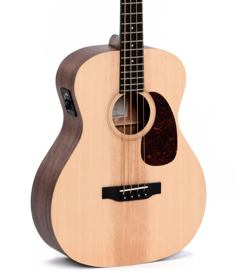 Acoustic bass guitar with a light wood top, dark wood sides, four strings, round sound hole, dark pickguard, and built-in electronic controls on the side.