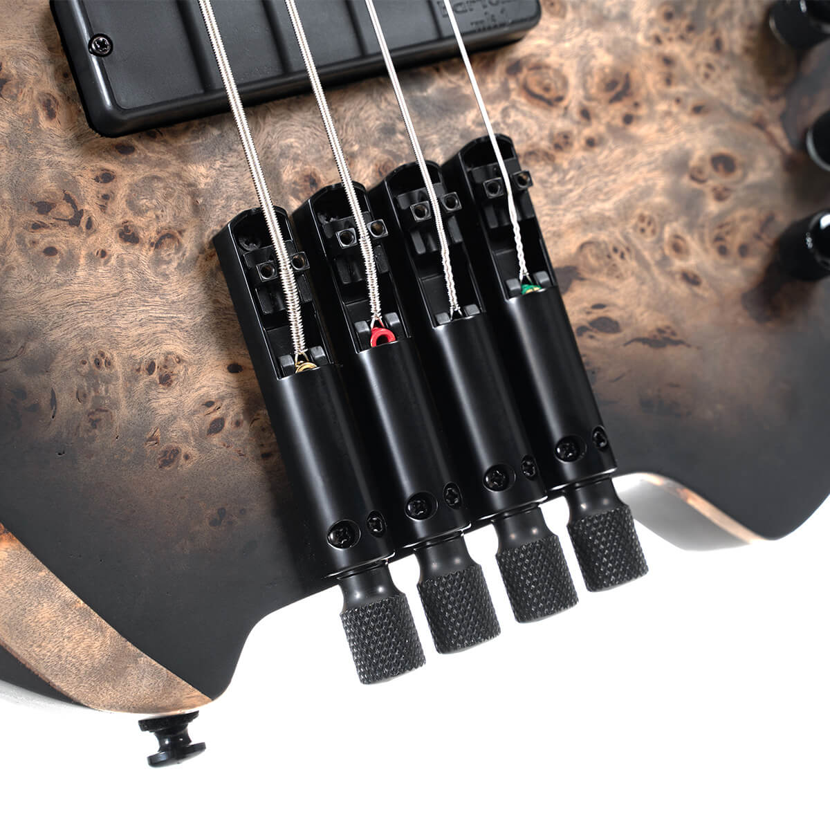 Close-up of a bass guitar’s body showing four metal tuning knobs and bridge on a wood grain finish.