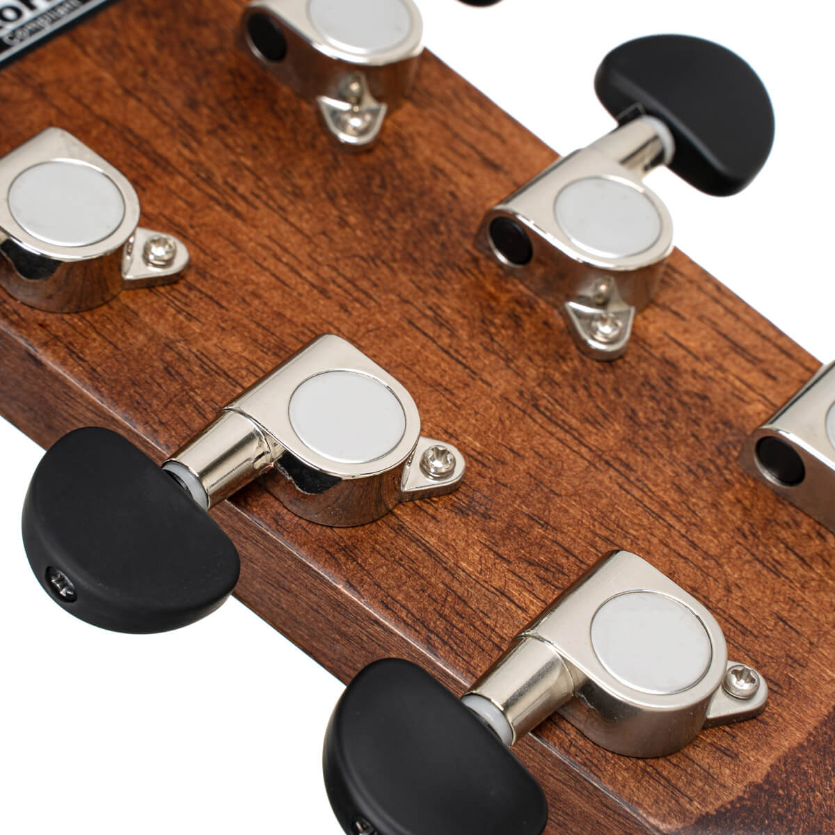 Close-up of the back of an acoustic guitar headstock showing six chrome tuning pegs with black plastic knobs on a wood surface.