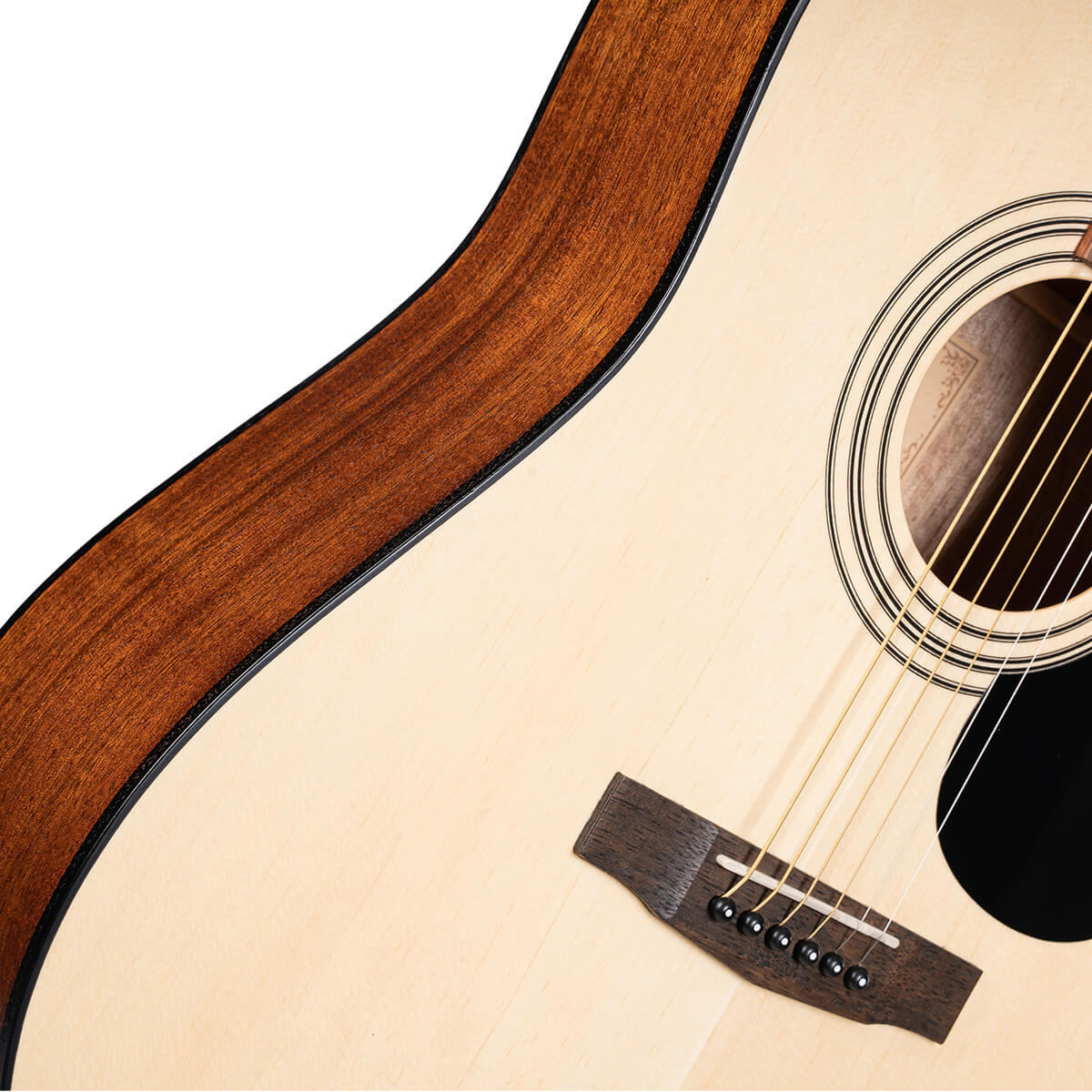 Close-up of an acoustic guitar showing a light wood top, dark wood side, round sound hole, six strings, and a dark bridge with white pins.