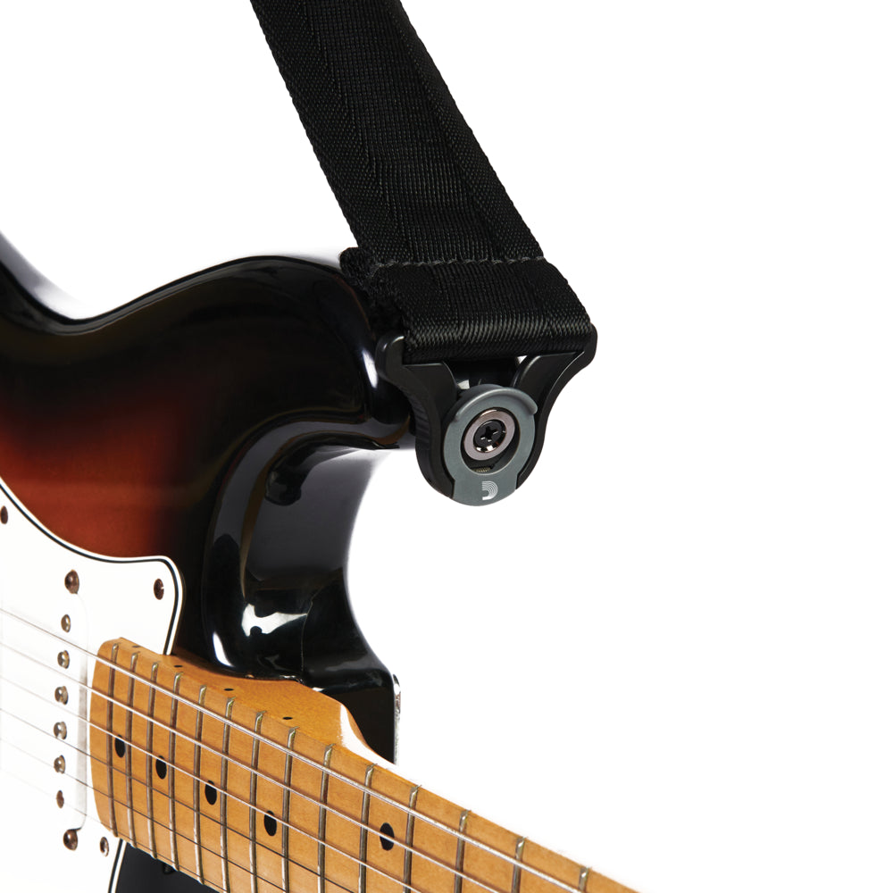 A black guitar strap securely fastened to an electric guitar using a locking strap button accessory near the neck joint.