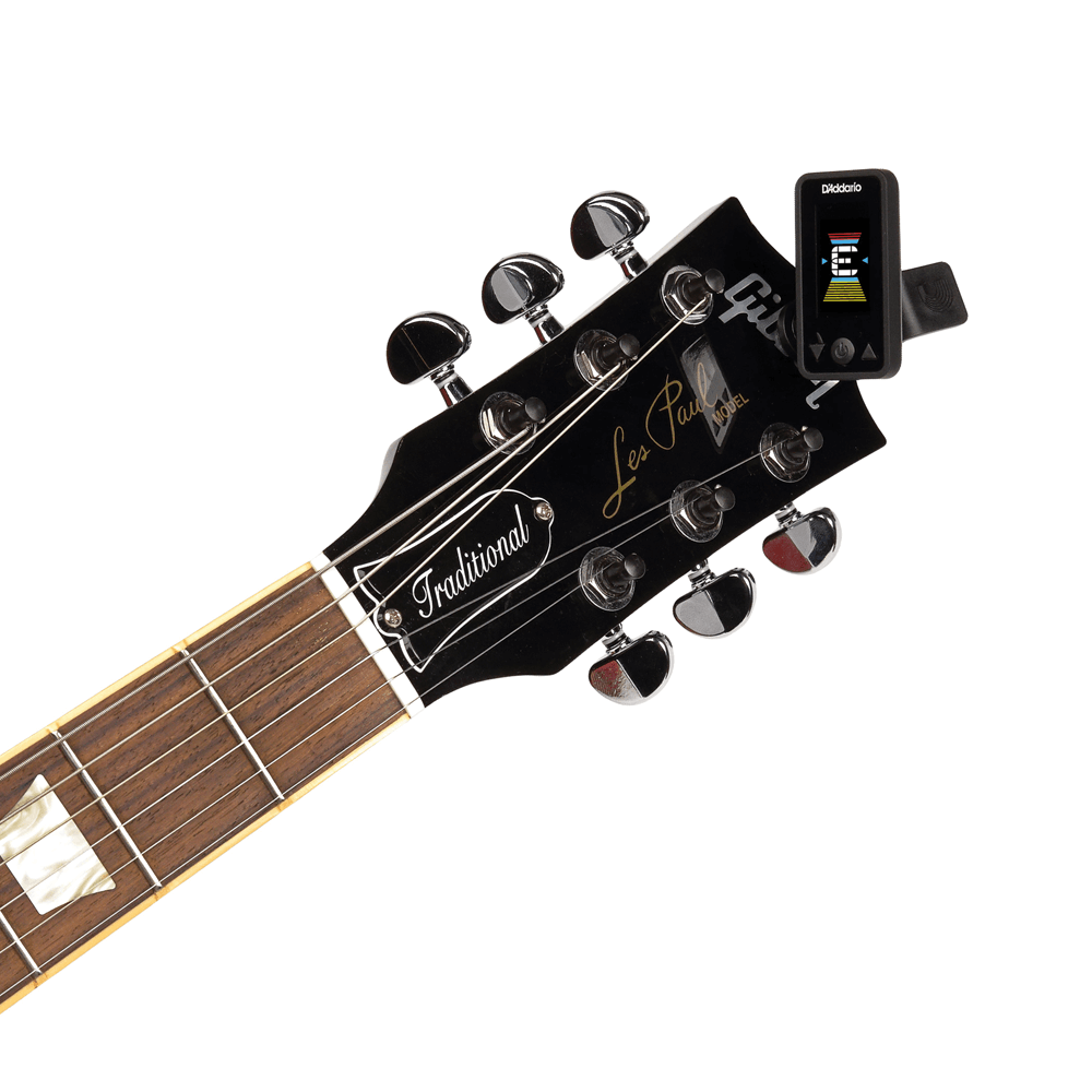 A clip-on tuner attached to the headstock of a Gibson Les Paul guitar, displaying tuning information on its screen.