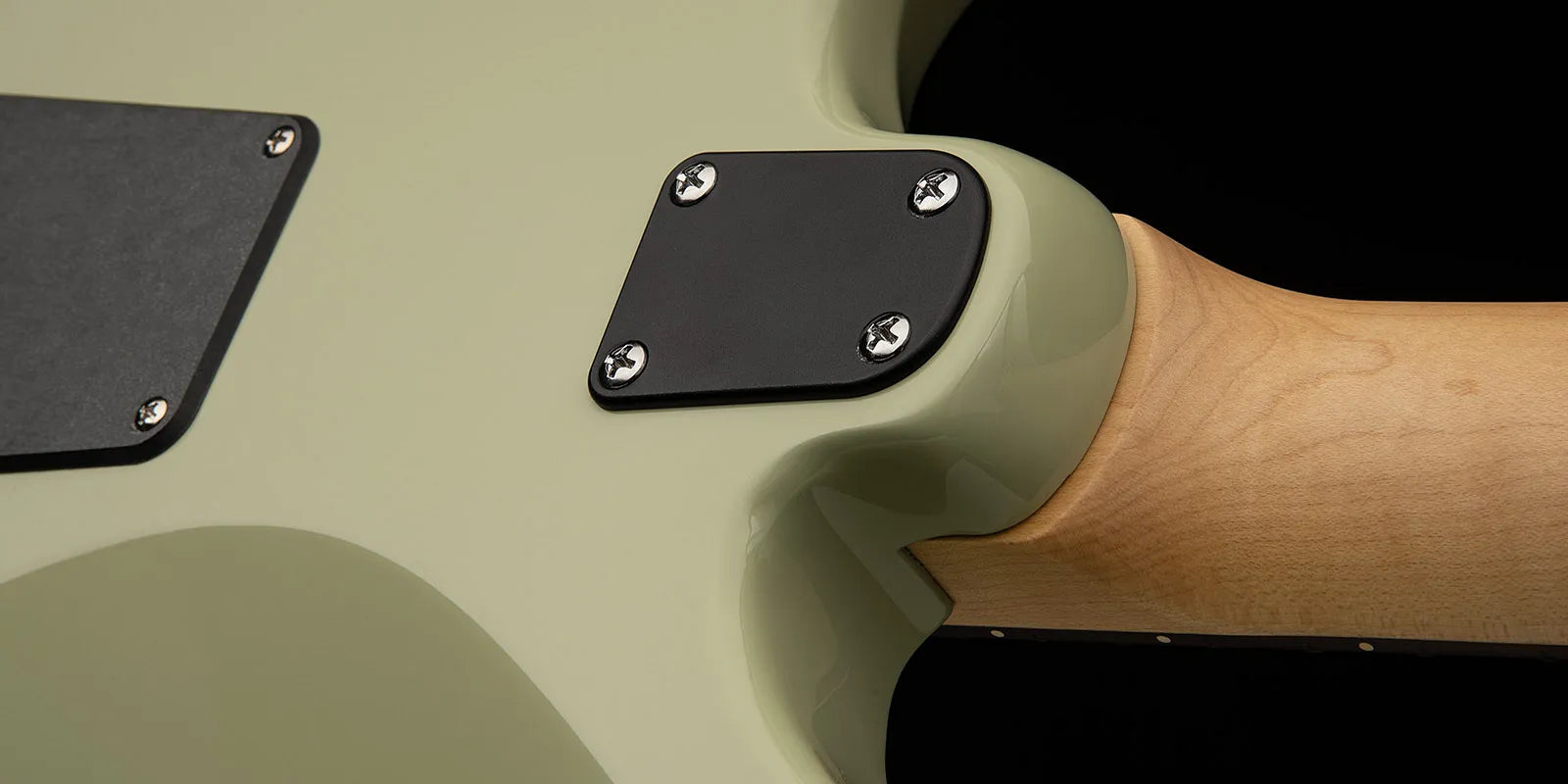 Close-up of a Paul Reed Smith guitar’s green back and neck joint, showing two black plastic cover plates secured by screws.