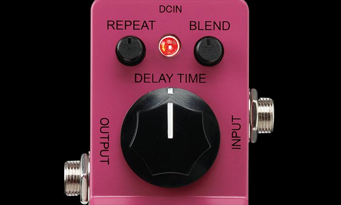 Pink FX pedal with large center knob labeled Delay Time, two smaller knobs for Repeat and Blend, a red LED, and input/output jacks on each side.