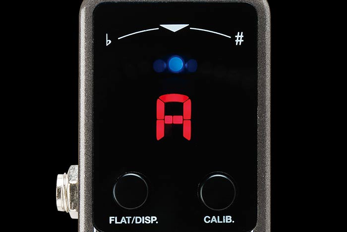 Pedal tuner display shows the note “A” in red, with two black buttons labeled FLAT/DISP. and CALIB. and tuning indicators above.