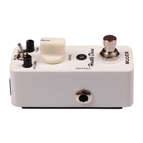 Compact white effects pedal with volume, tone, and drive knobs, a footswitch, a toggle switch, and a single output jack on the front.