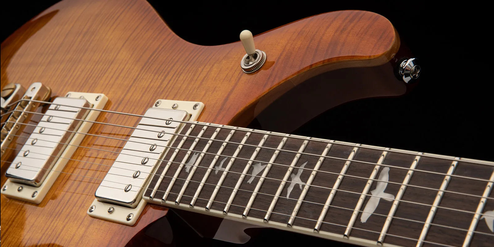 Sunburst electric guitar with dual chrome humbucker pickups and bird-shaped inlays on the dark fretboard. Pickup selector switch is visible.