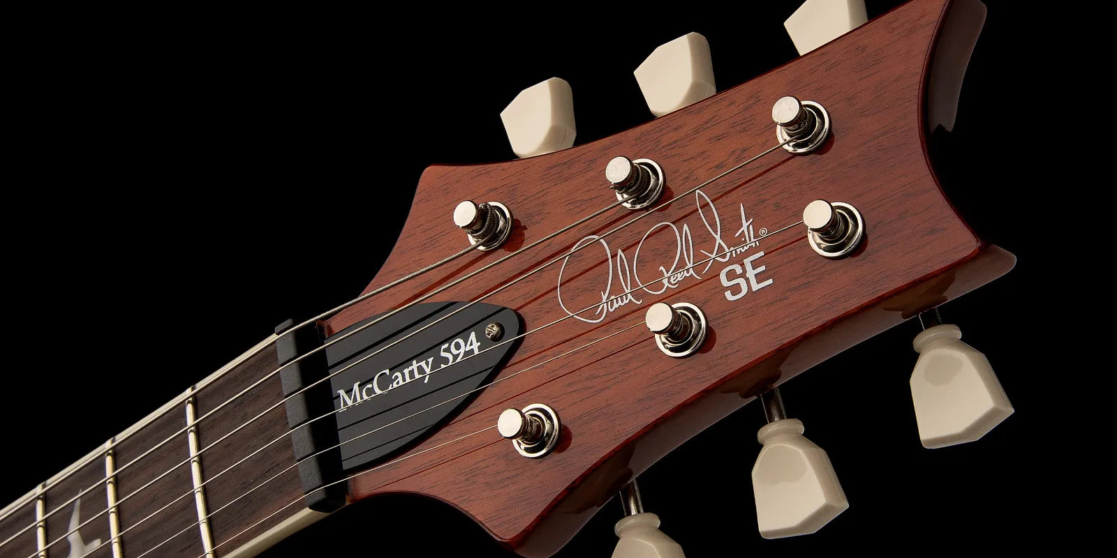 Close-up of a PRS SE electric guitar headstock with six tuning pegs, Paul Reed Smith signature, and “McCarty 594” truss rod cover.
