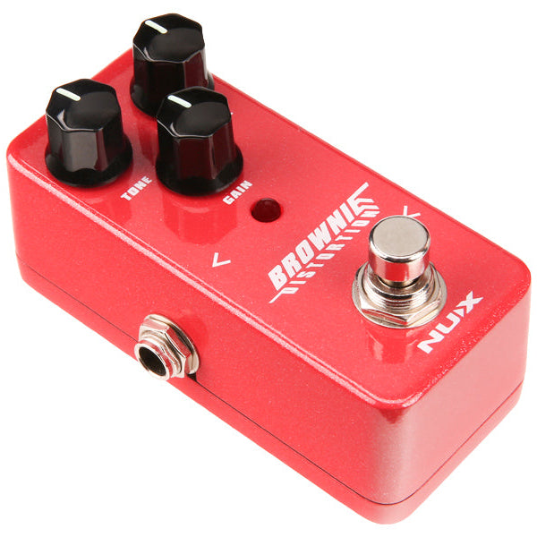 Red NUX Brownie distortion FX pedal with three black knobs labeled volume, tone, and gain, a footswitch, jack input, and LED indicator.