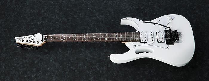 White electric guitar with a unique cutaway body, three pickups, whammy bar, and vine inlay design on the dark fretboard.