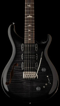Black electric guitar with three pickups, a whammy bar, bird inlays on the fretboard, and an f-hole on the upper left side of the body.