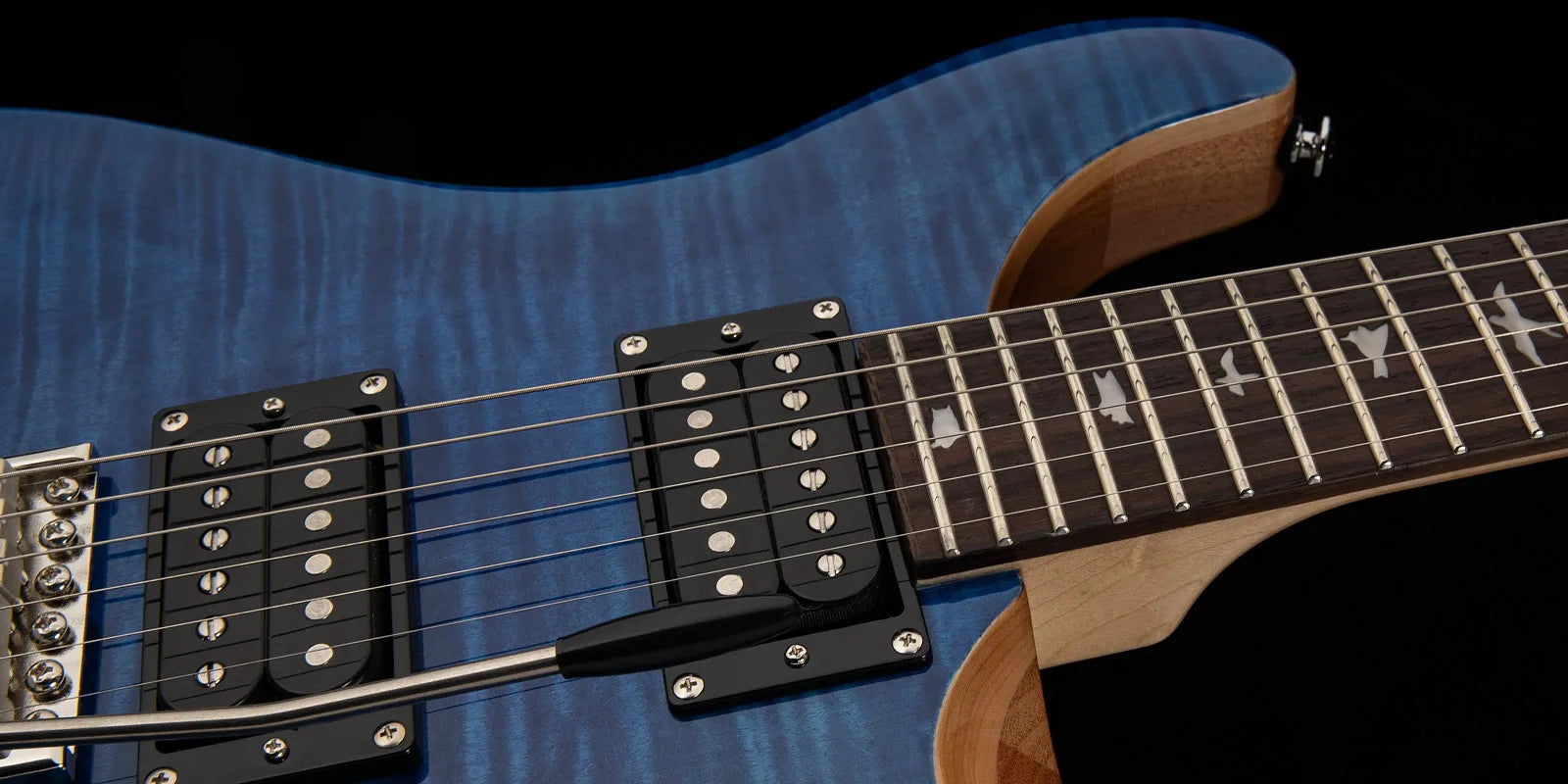 Blue-bodied electric guitar with two black humbucker pickups, a tremolo arm, and bird inlays on a dark fretboard.