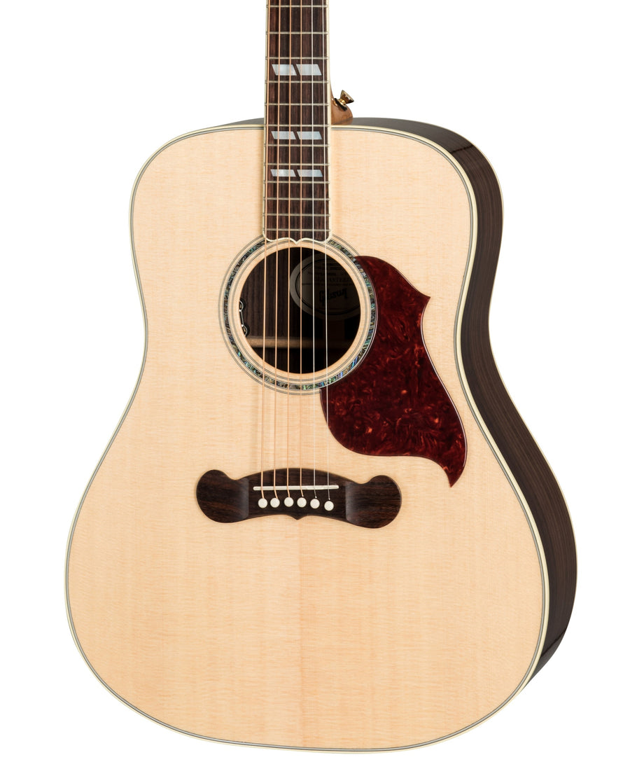 Light wood acoustic guitar with a dark tortoiseshell pickguard, abalone rosette, and dark wood bridge with white pins.