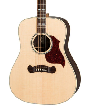 Light wood acoustic guitar with a dark tortoiseshell pickguard, abalone rosette, and dark wood bridge with white pins.