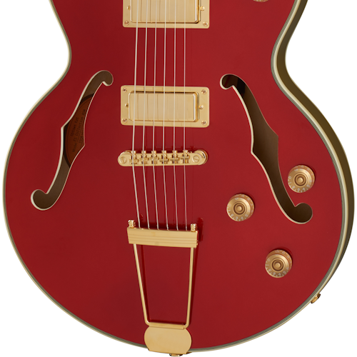 Red electric guitar with two f-shaped sound holes, gold pickups, bridge, tailpiece, and control knobs on the lower right side.
