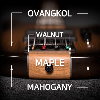 Close-up of a bass guitar bridge showing labeled woods: ovangkol top, walnut center, maple bottom front, and mahogany below maple.