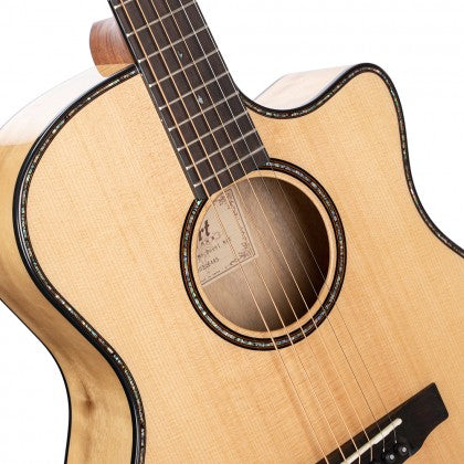 Light wood acoustic guitar with a single cutaway, dark edge binding, round sound hole, and six steel strings visible.