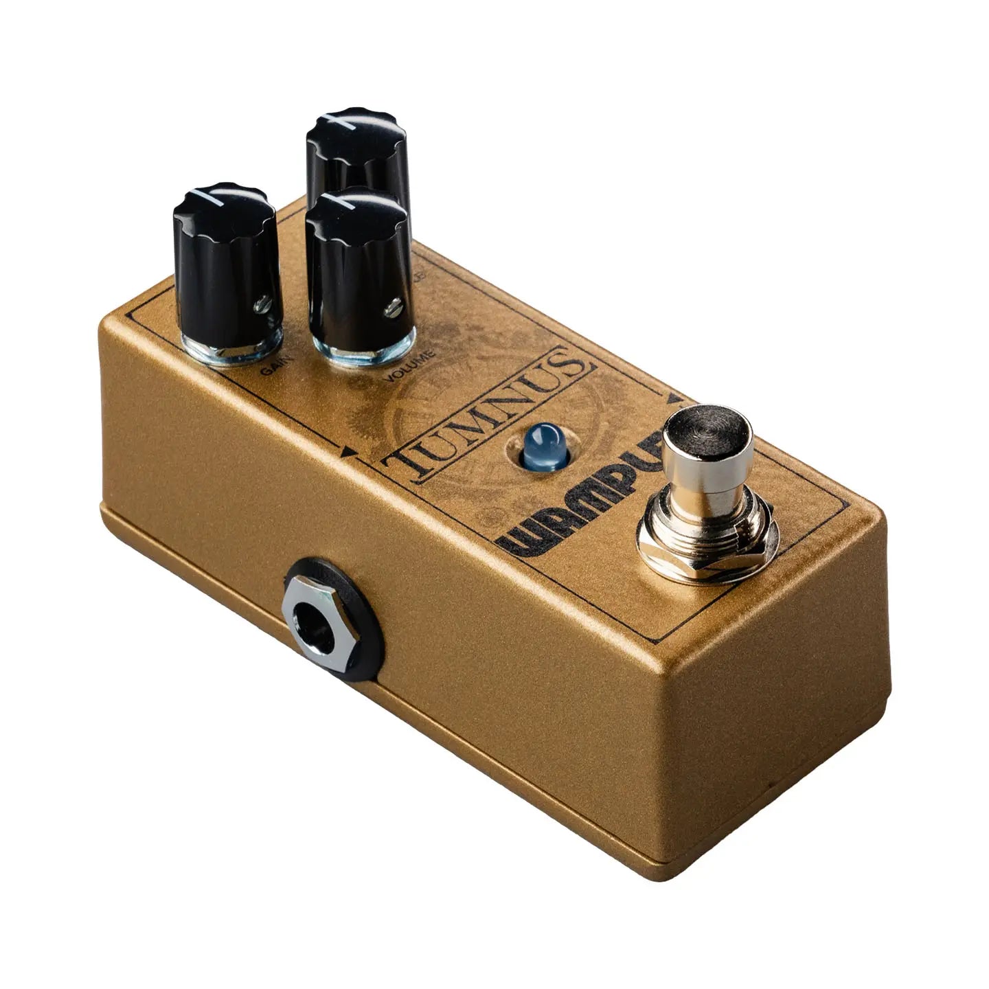 Gold rectangular guitar effects pedal with three black knobs, a blue LED, footswitch, and side input jack; labeled Tumnus by Wampler.
