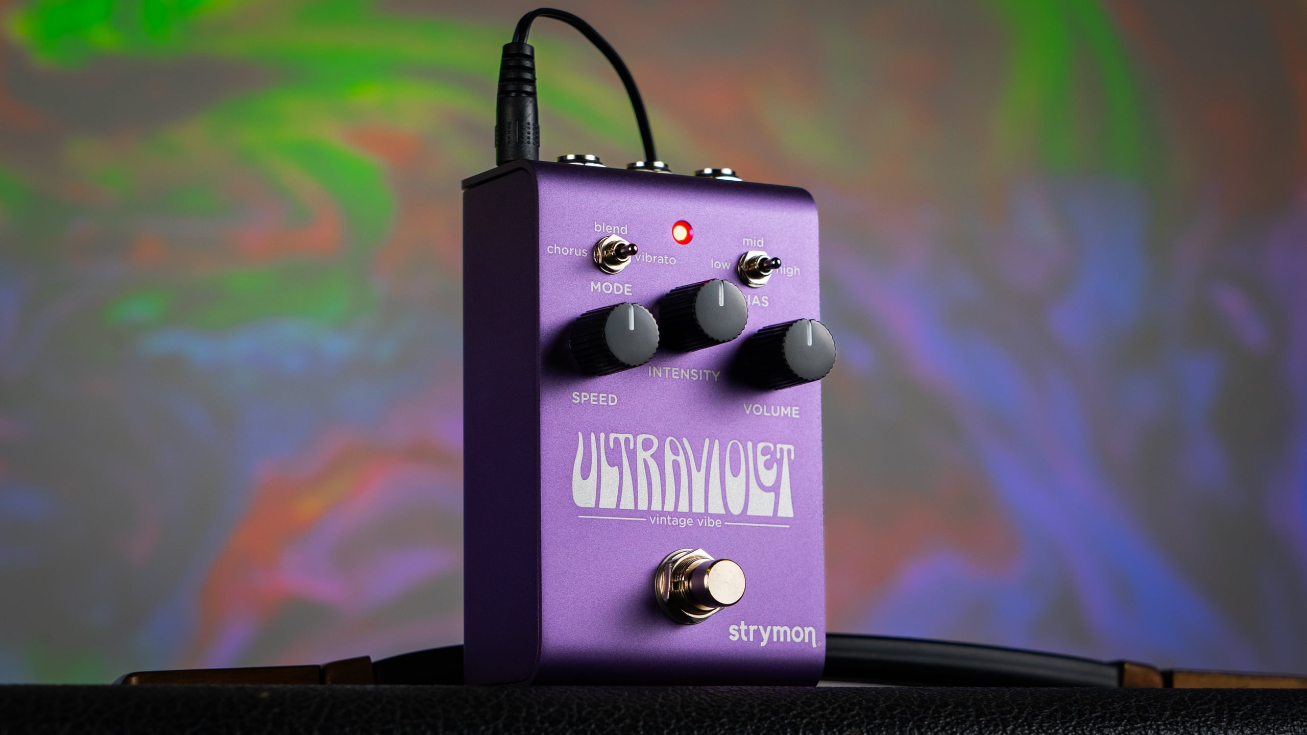 Purple FX pedal labeled "Ultraviolet" with three knobs, two toggle switches, a footswitch, and an LED light, sitting on a textured surface.
