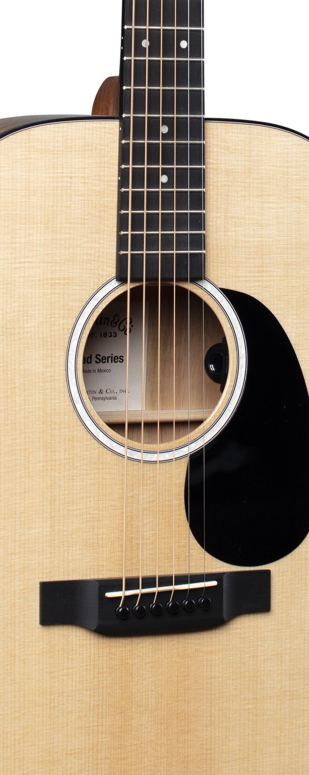Light wood acoustic guitar body with six strings, black pickguard, circular sound hole, and visible frets on the neck.
