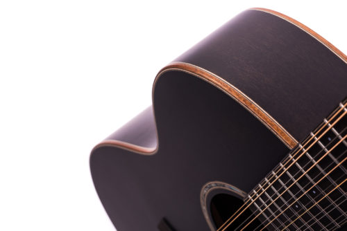 Close-up of a dark wood acoustic guitar body, showing the curved edge, soundhole, and several strings on a white background.