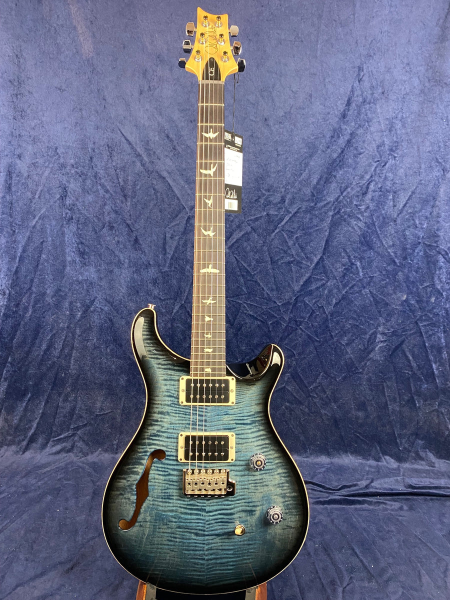 Blue electric guitar with semi-hollow body, two humbucker pickups, bird inlays on the fretboard, and a whammy bar.