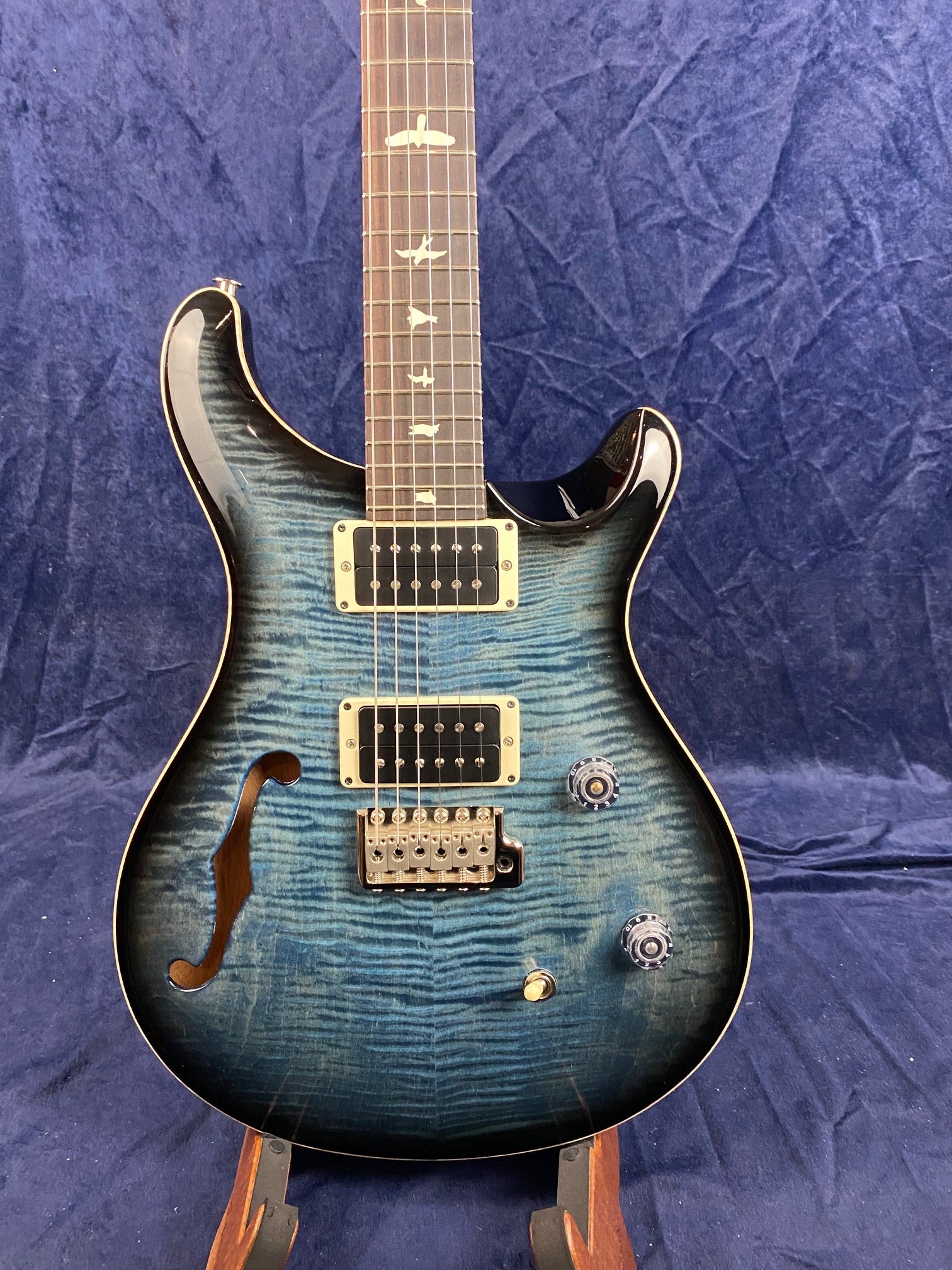 Blue electric guitar with a semi-hollow body, two humbucker pickups, bird inlays on the fretboard, and two control knobs.