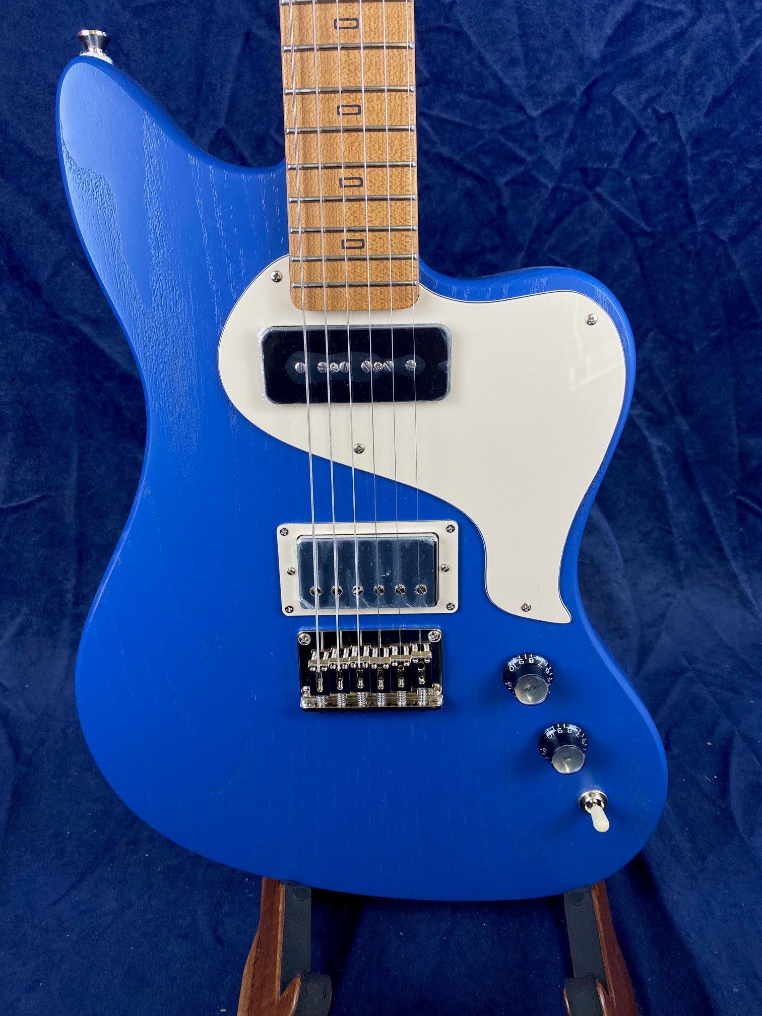 Electric guitar with a bright blue body, white pickguard, two pickups, two control knobs, and a wooden neck with marked frets.