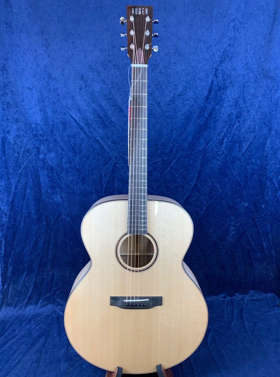 Light wood acoustic guitar with a dark wood neck and headstock, silver tuning pegs, and "AUDEN" in white letters on the headstock.