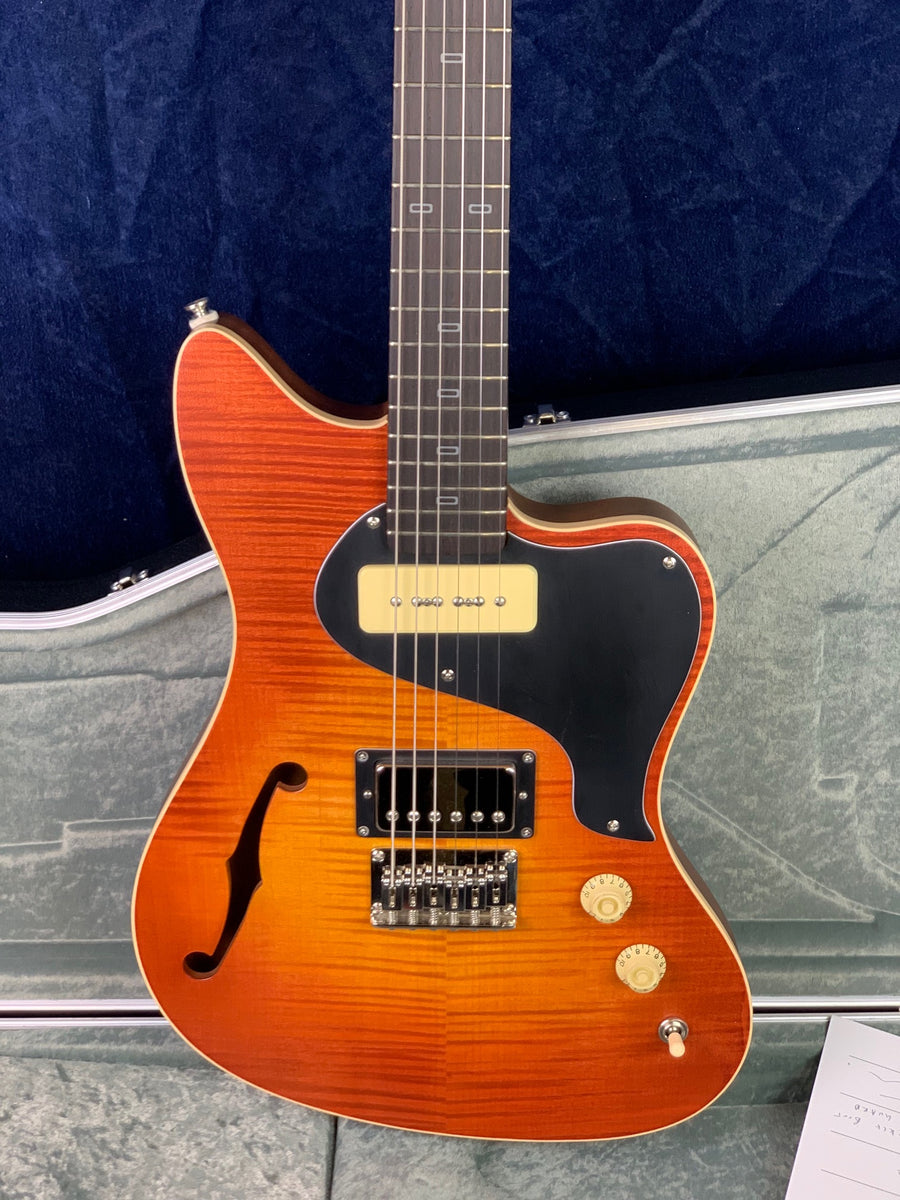Sunburst electric guitar with a semi-hollow body, black pickguard, two pickups, two control knobs, and an f-shaped sound hole on the left.