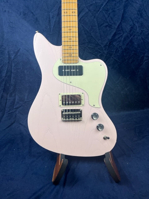 Light pink electric guitar with a white pickguard, two pickups, three control knobs, and a natural wood neck, set against a dark blue background.