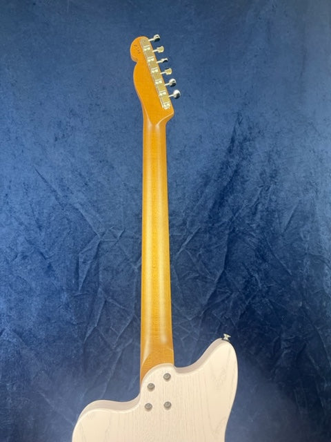 Electric guitar shown from the back against a blue background, displaying a natural wood neck, tuners, and part of a white wood body.