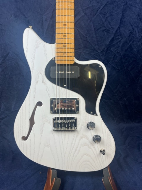 White electric guitar with a black pickguard, maple neck, single f-hole, two pickups, three control knobs, and a cutaway body shape.