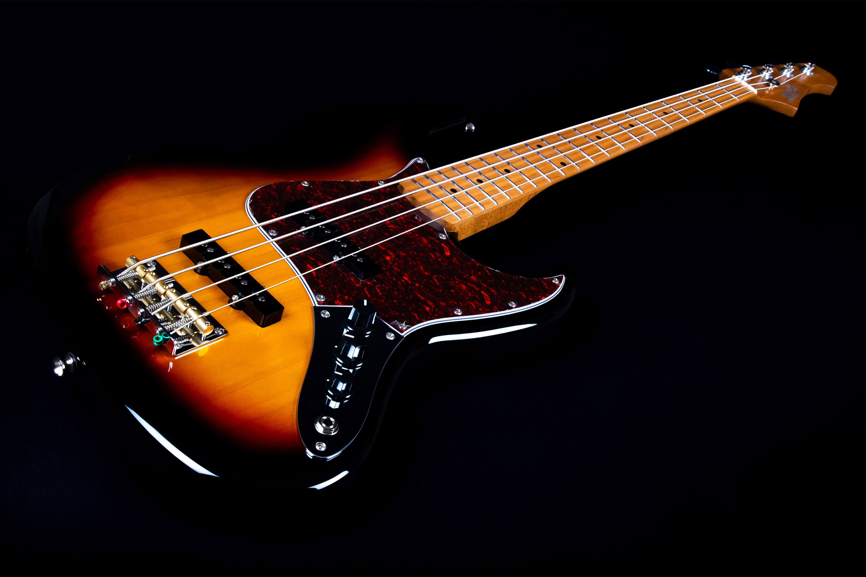 Sunburst finish bass guitar with a wooden neck, four strings, dark red pickguard, silver control knobs, and a gold bridge.