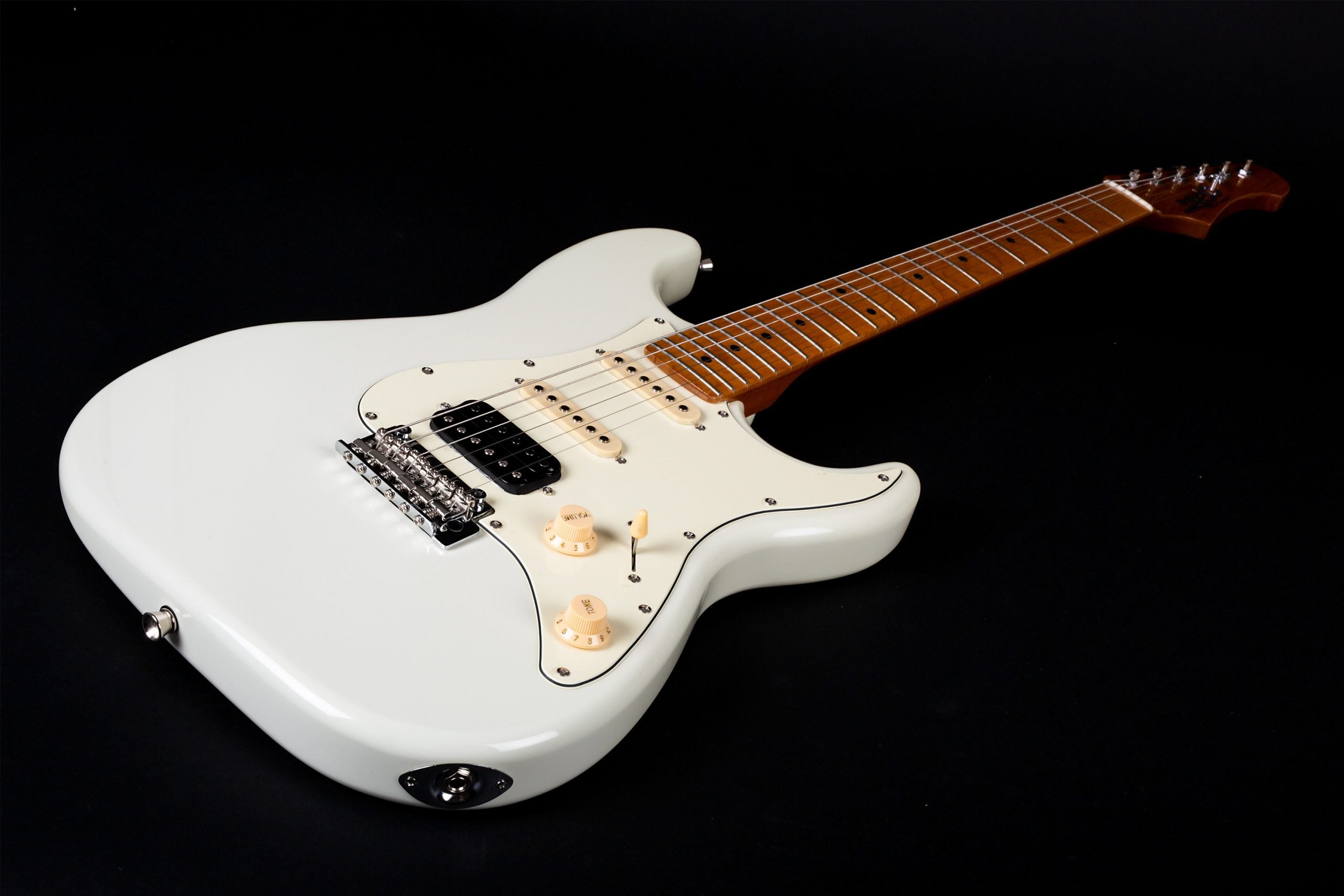 White electric guitar with a maple neck, three pickups, cream knobs, and a white pickguard, lying on a black background.