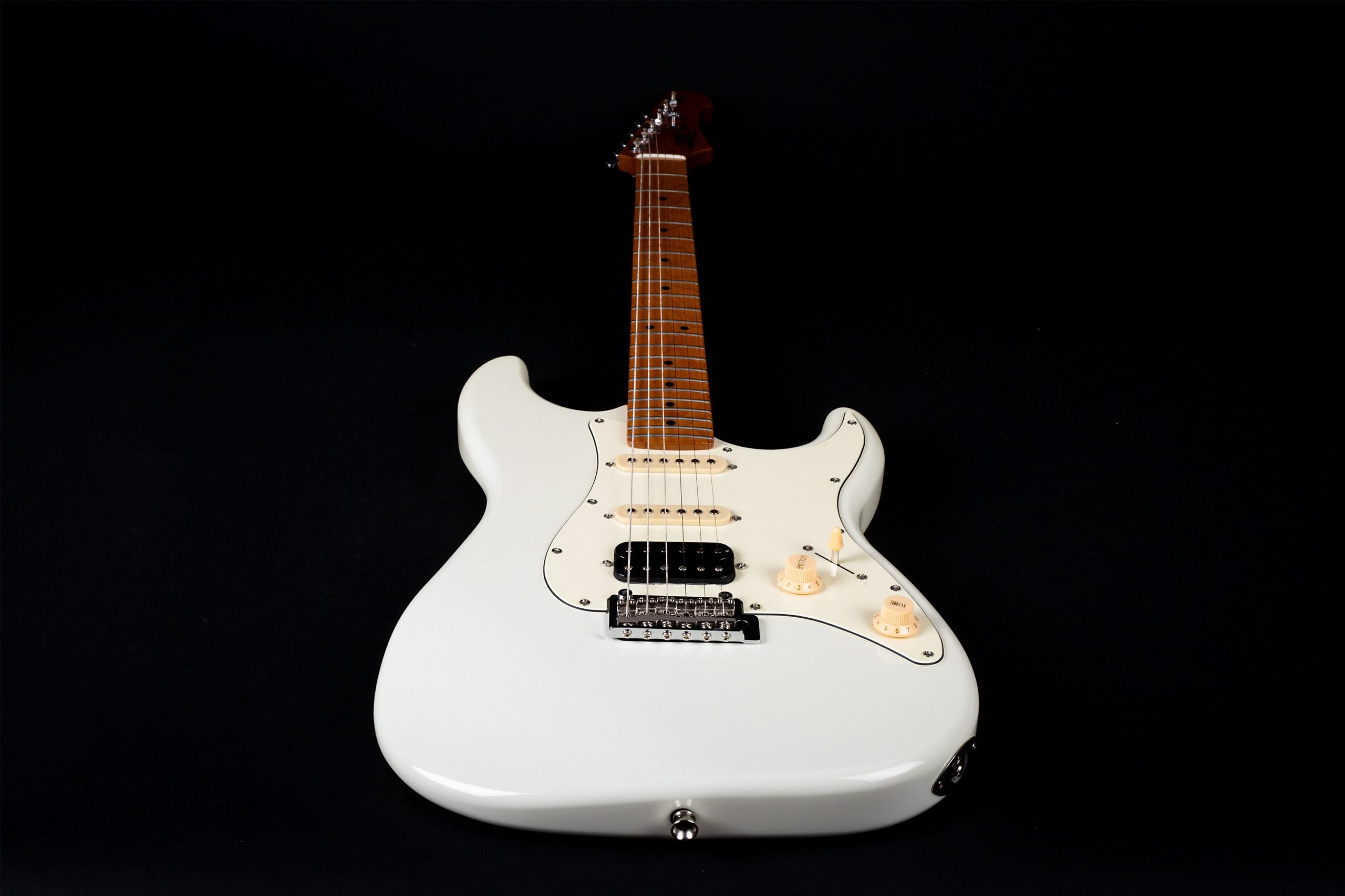 White electric guitar with a light brown neck, three pickups, and two control knobs, photographed against a black background.