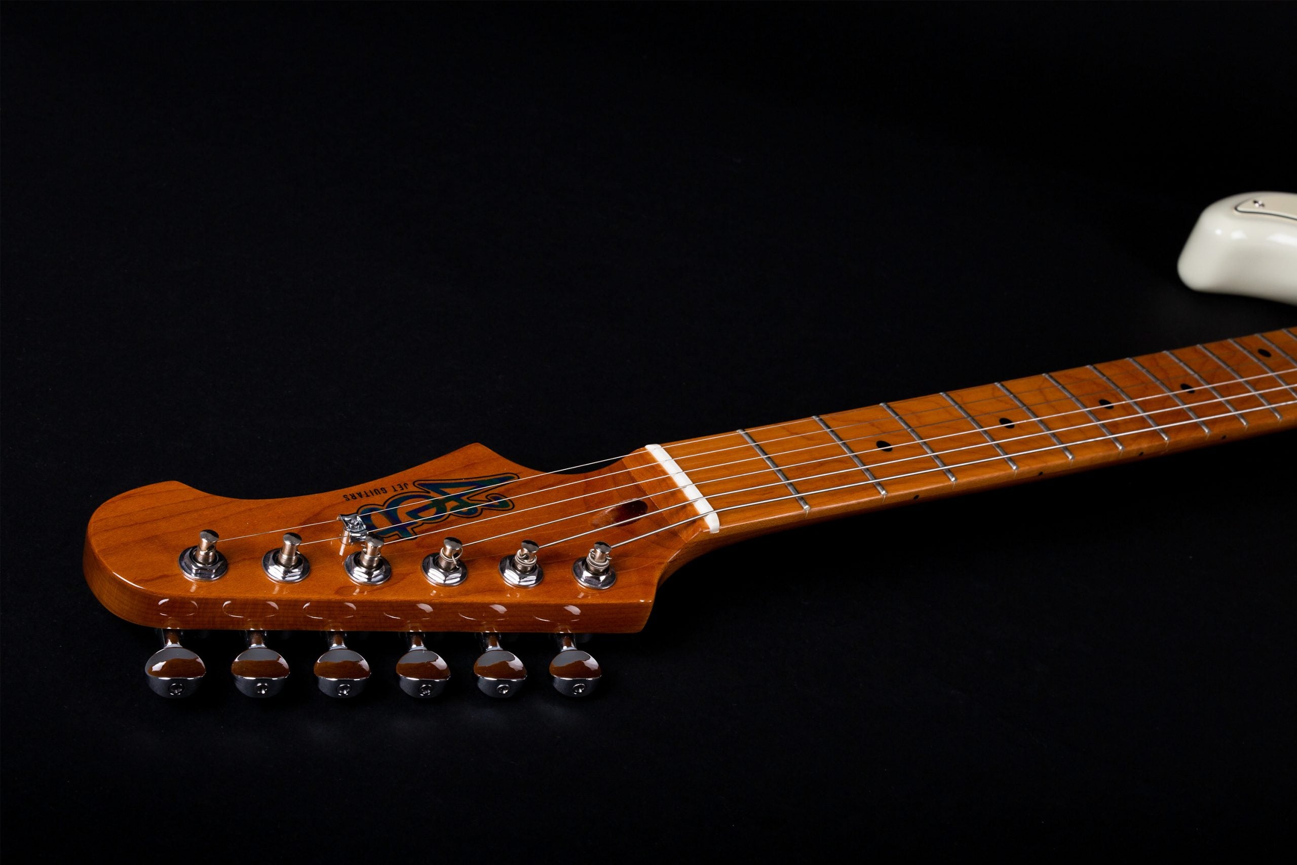 Light brown electric guitar neck and headstock with six metal tuning pegs, strings, and dot inlays on the fretboard, placed against a black background.