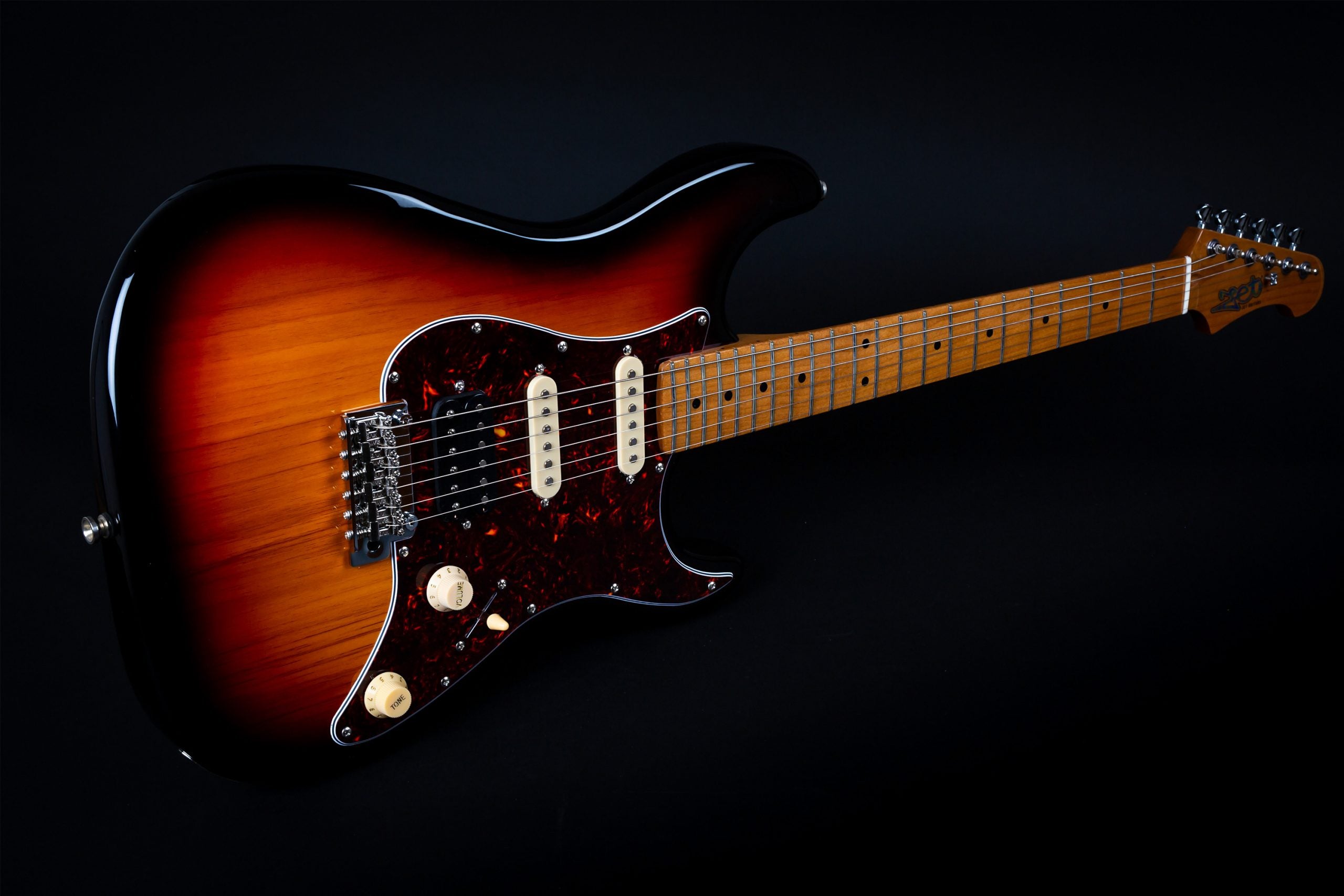 Sunburst electric guitar with a brown tortoiseshell pickguard, cream knobs, three single-coil pickups, and a maple neck with dot inlays.