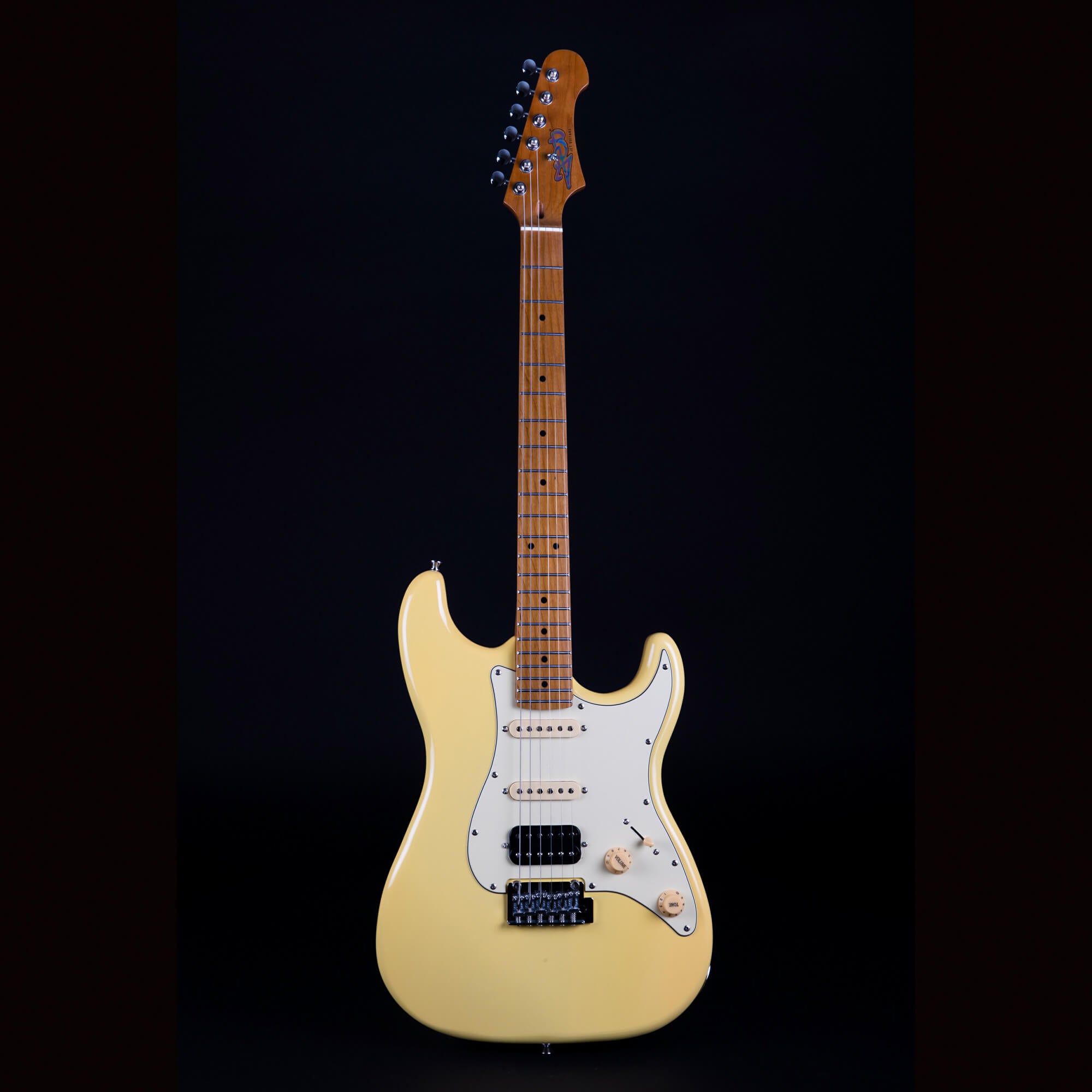 Cream-colored electric guitar with a white pickguard, three pickups, maple neck, and six tuning pegs against a black background.