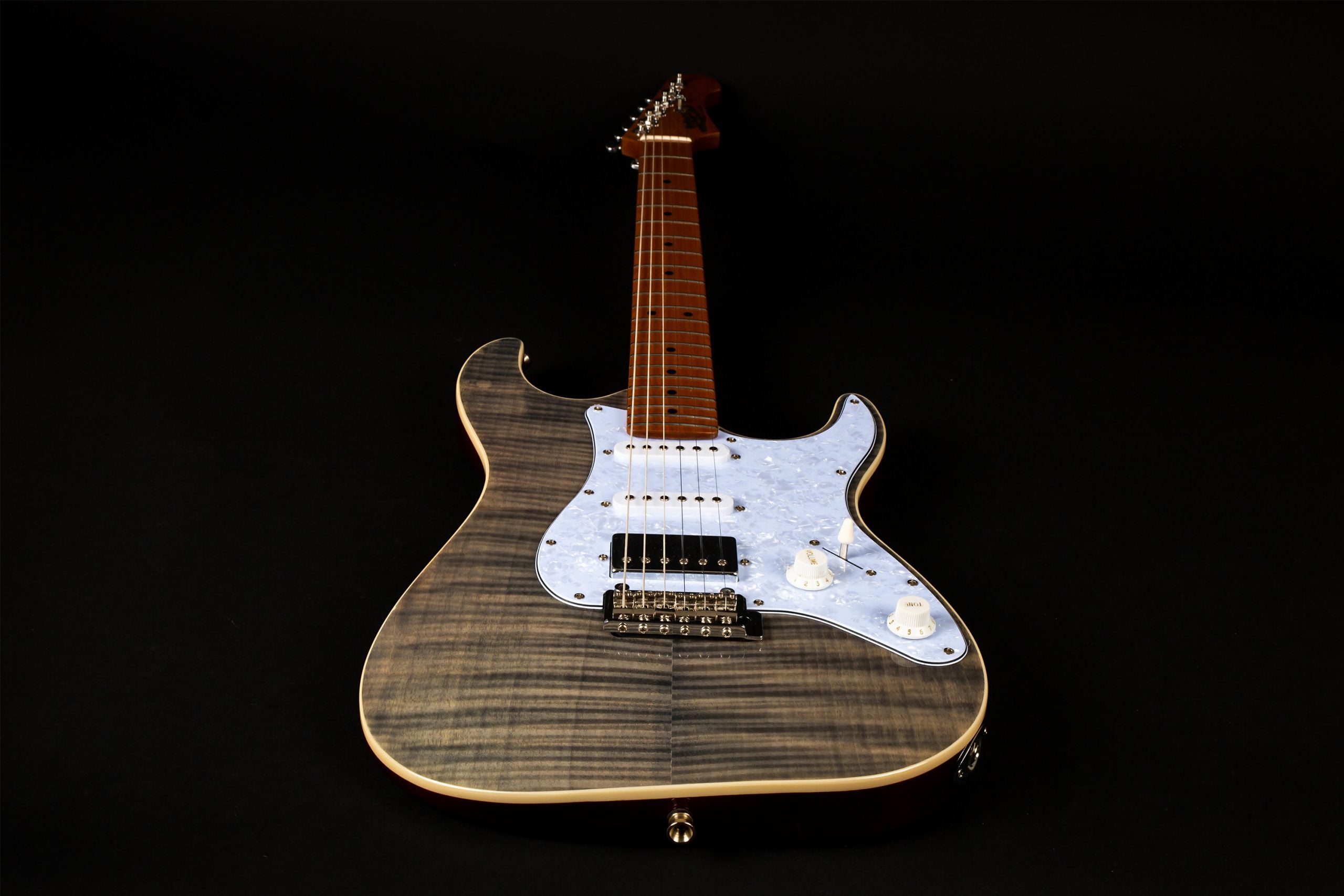 Electric guitar with a glossy, striped grey wood finish, white pearloid pickguard, three pickups, and maple neck, positioned on a black background.