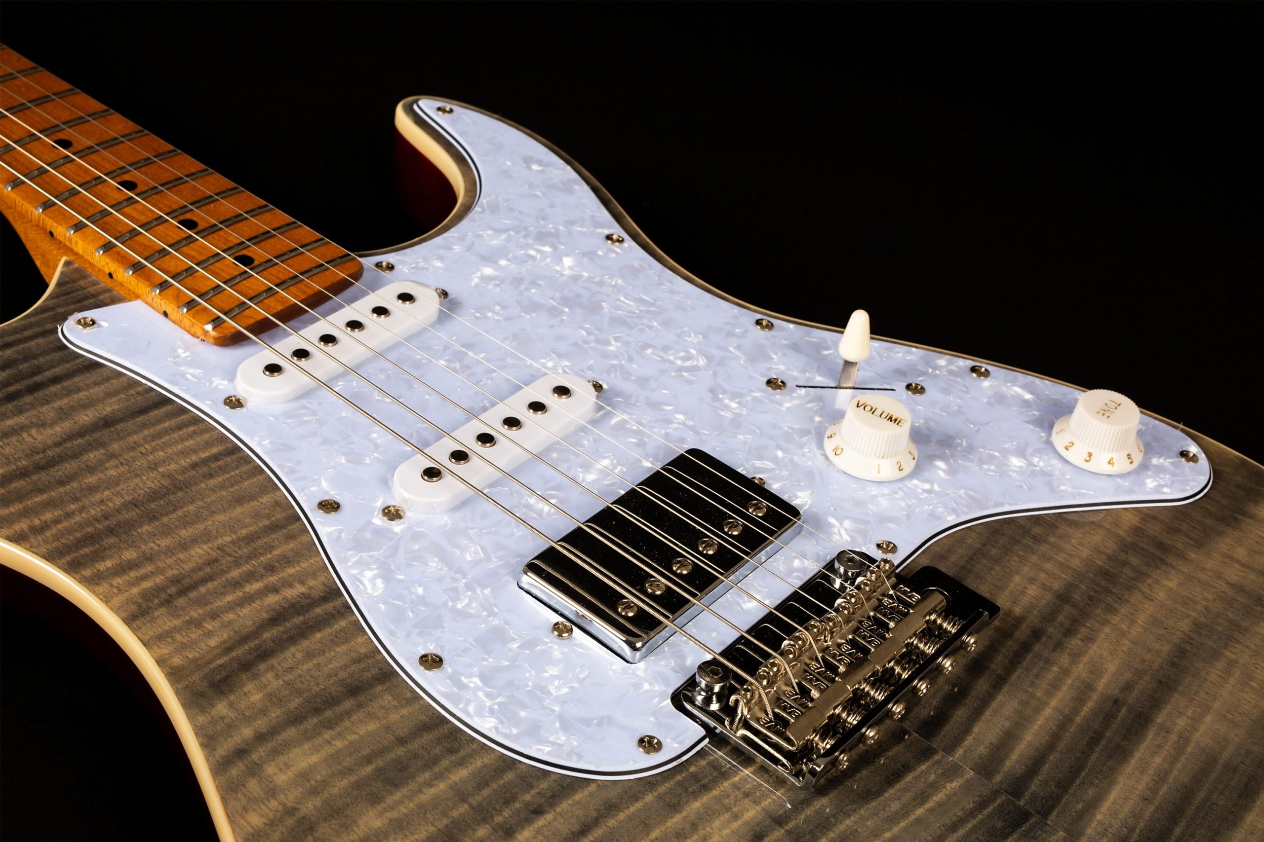 Electric guitar with a striped gray wood finish, white pearl pickguard, two white single-coil pickups, one chrome humbucker, and chrome bridge.