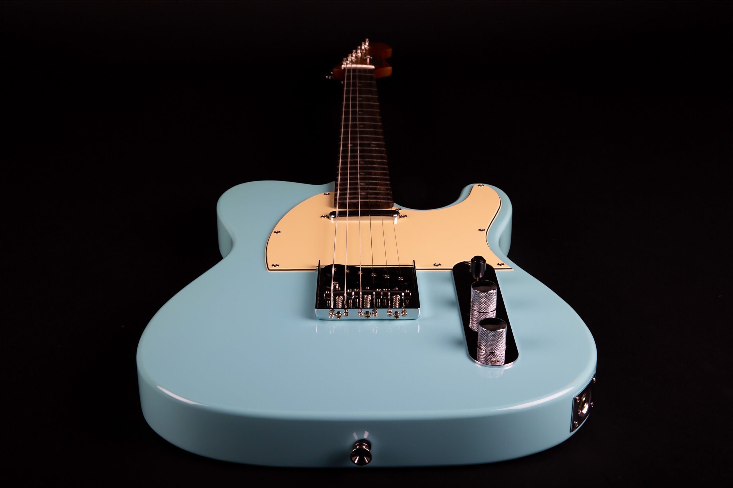 Light blue electric guitar with a cream pickguard, chrome bridge, and two textured control knobs, shown from the body facing down the neck.