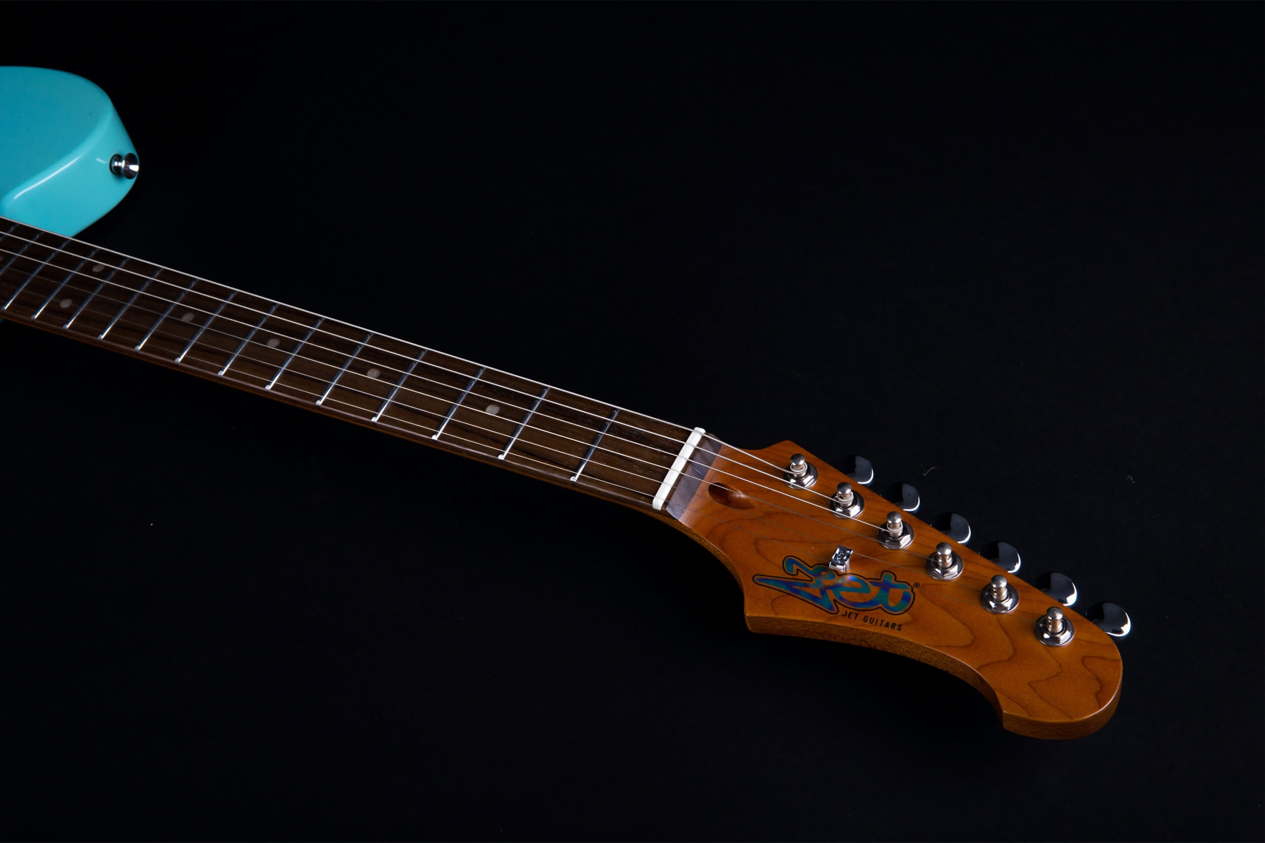 A wooden electric guitar neck with silver frets, dot inlays, and six tuning pegs, attached to a turquoise guitar body.