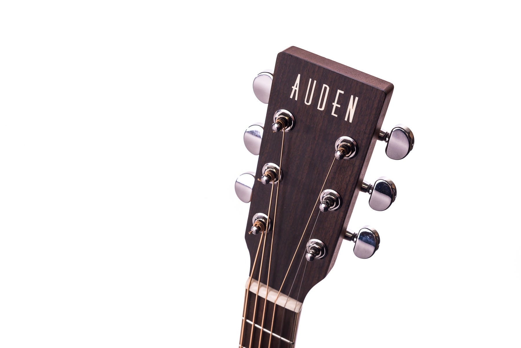 Dark wood acoustic guitar headstock with six silver tuning pegs and "AUDEN" written in white capital letters on the front.