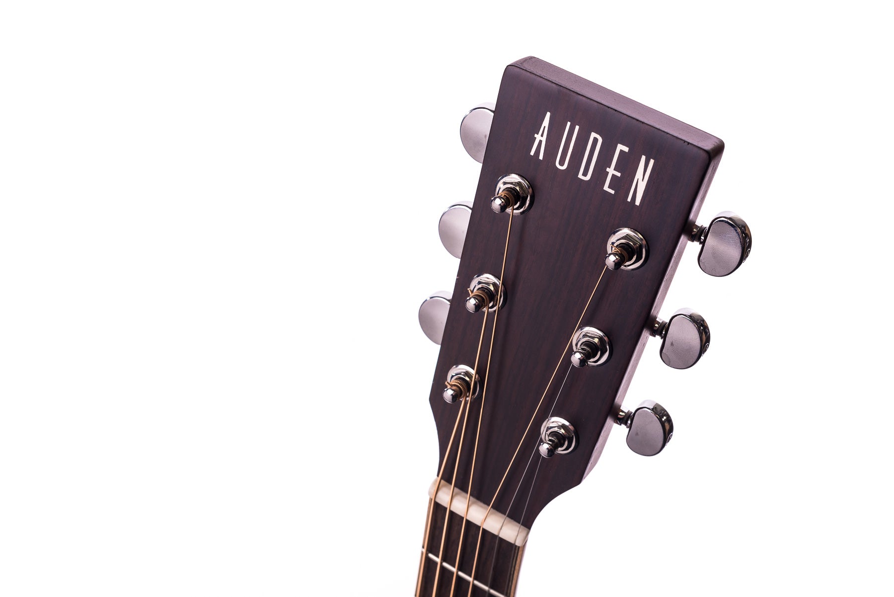 Close-up of an acoustic guitar headstock with six tuning pegs and "AUDEN" in white letters on dark wood.