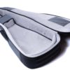 A soft, padded gray guitar case lies open, showing its plush interior and protective side padding designed for an acoustic guitar.