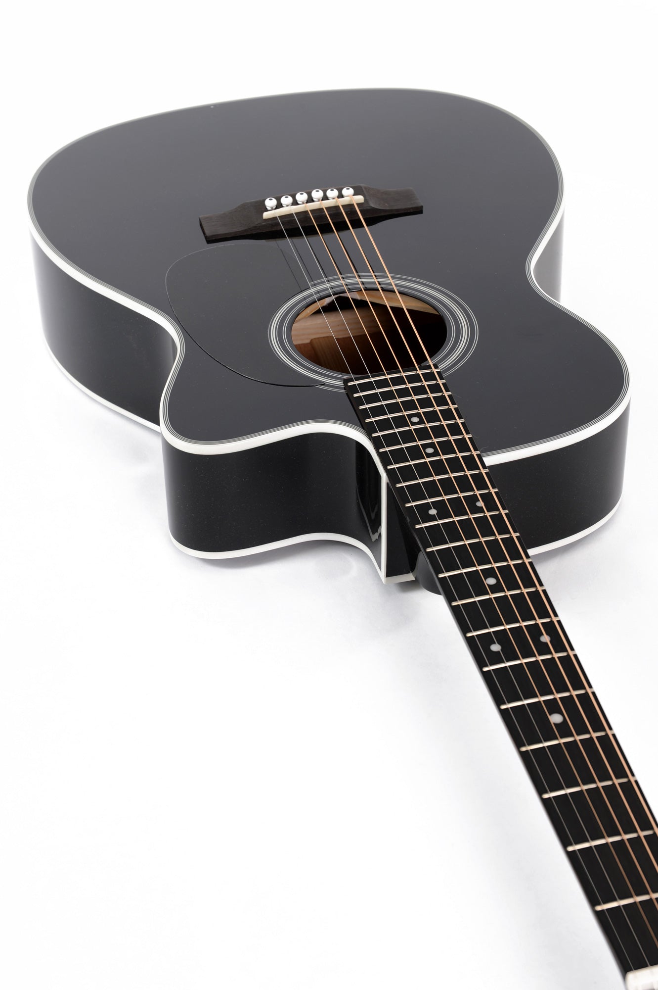 Glossy black acoustic guitar with white trim, round sound hole, six strings, and dot inlays on the fretboard, viewed from the body toward the neck.